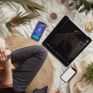 personne devant un écran et deux téléphones