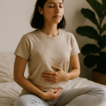 femme en position de méditation, les yeux fermés avec une main sur le cœur et l'autre sur le ventre. Sur son lit avec une plante à côté